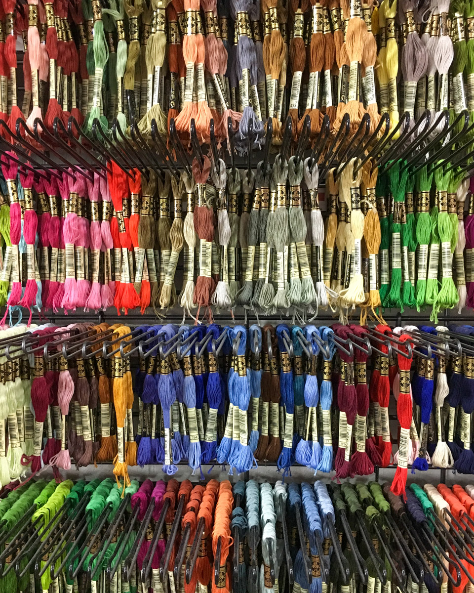 A wall display of embroidery floss in dozens of bright colours
